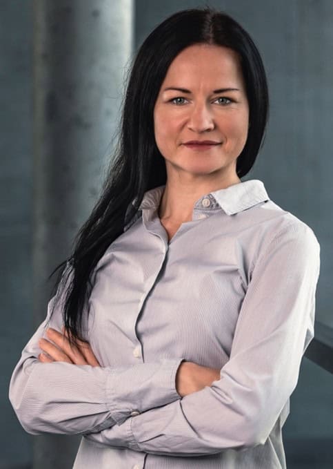 Profesjonalna kobieta w biznesowym otoczeniu, prezentująca ekspertkę podczas wydarzenia PHD RISK Summerschool, związana z tematyką ryzyka i edukacji.